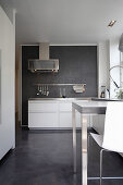 White cupboard and counter with bar stools in kitchen with concrete floor