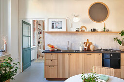 Küchenzeile mit Holzfront, darüber handglasierte Fliesen und Regal