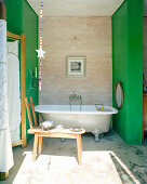 Free-standing bathtub between green walls