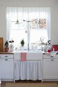 A white rural kitchen with a sink in front of the window