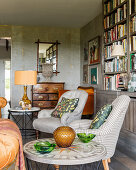 Pair of upholstered chairs with bookcase and glass ornaments