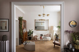 Blick ins helle Wohnzimmer mit Polstermöbeln, Wandspiegel und antiker Anrichte