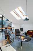 Round table and armchairs under skylight in loft apartment