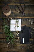 Adventskalender herstellen: Weiß verpacktes Geschenk, Wacholderwzeig und schwarzer Fotokarton mit Nummer