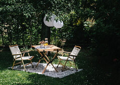 Table and chairs on rug in garden