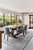 Wooden dining table and grey upholstered chairs next to window