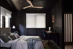 Doppelbett und Arbeitsecke im Schlafzimmer mit dunkelbrauner Wand