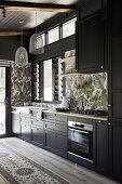 Fitted kitchen with dark cupboard fronts, tiles with tropical motif as splashback