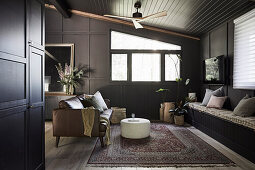 Custom-made bench with storage space and leather sofa in the living room with dark brown walls
