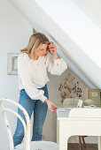 Blonde woman standing next to the desk in attic room