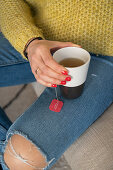Woman's hand holding mug of tea with tea bag