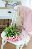 Pink tulips and wooden bunny on a white chair