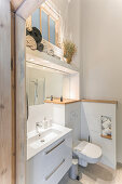 View of wash basin with base cabinet and toilet in high-ceilinged bathroom