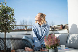 Blonde Frau in Freizeitbekleidung sitzt auf der Terrasse