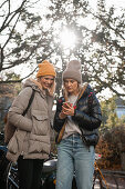 Two women in autumn clothing looking at a smartphone