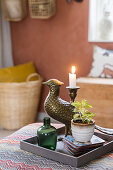 Candlestick, bird figurine, glass bottle and a potted plant on a tray