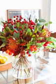 Colorful bouquet with protea in glass vase on dining table