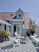 Sunny roof terrace with seating, plant pots and tiled floor