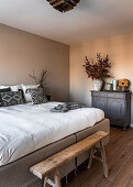 Double bed, rustic bench and chest of drawers in bedroom