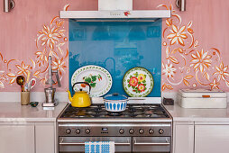 A Swedish folklore inspired mural frames the gas stove and range in the kitchen
