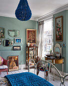 Vintage Spiegel, Kunstwerke an der Wand und Perlenkronleuchter im hellen Schlafzimmer mit blauen Wänden