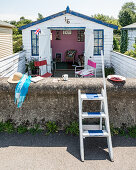 A view of a beach hut over a stone wall