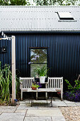 Seating area outside house clad in black corrugated iron