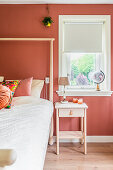 Simple, Scandinavian furniture in bedroom with terracotta-coloured walls