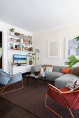 Grey sofa set, armchairs with metal structure and shelves in living room with dark rug