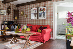 Living room with red sofa, wooden table and tartan wallpaper