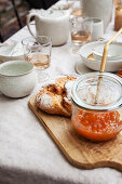 Selbstgemachte Aprikosenmarmelade und frisches Brot auf gedecktem Tisch