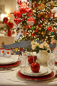 Table set for Christmas meal with toffee apple on place setting and Christmas tree in the background