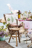 Kissen mit botanischem Druck auf Stuhl, Hocker und festlich gedeckter Tisch am See