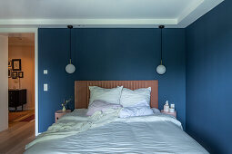 Double bed and two reading lamps in bedroom with blue walls