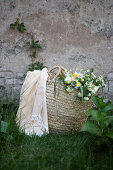 White bouquet of peonies, viburnum, feverfew and grasses in basket bag