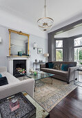 Elegant lounge with grey sofas and antique mirror above fireplace