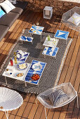 Gedeckter Tisch mit Vorspeisen, blau-weiße Beistelltische und Sitzmöbel auf Terrasse