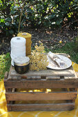 Spools of yarn, jam jar, flower, plate and napkin on wooden box
