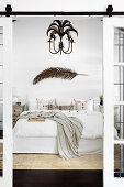 Double bed with a dried palm branch and chandelier with palm tree motif above the bed