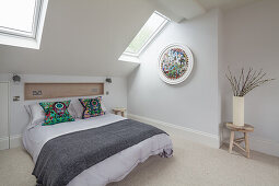 Doppelbett, darüber Wandnische mit Holzverkleidung in hellem Schlafzimmer mit Dachflächenfenstern