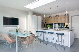 Dining area with rattan chairs in front of open-plan kitchen with kitchen island