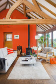 Sitzbereich mit orangefarbener Wand und Verglasung in umgebauter Scheune