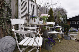Seating area next to garden fence with shutters and vintage-style decorations
