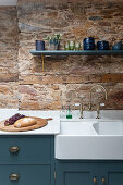 Kitchen cabinets with sink in front of exposed brickwork
