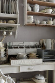 Shelves with porcelain dinnerware in the kitchen in shabby chic style