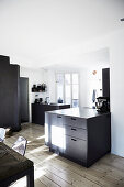Black furniture in white, light-flooded kitchen