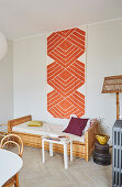 A wall hanging with a graphic pattern above a rattan day bed