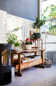 Wood-burning stove and wooden work bench against tiled wall in high-ceilinged conservatory