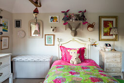 Wooden bed with colourful duvet, bench box and soft toys in rustic, child's bedroom