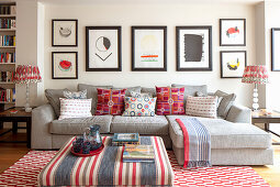 Sofa mit Kissen, darüber moderne, abstrakte Kunstsammlung